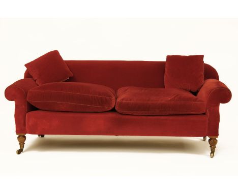 A Victorian overstuffed sofa, with red velour upholstery on turned mahogany feet terminating in brass casters, 200cm wide