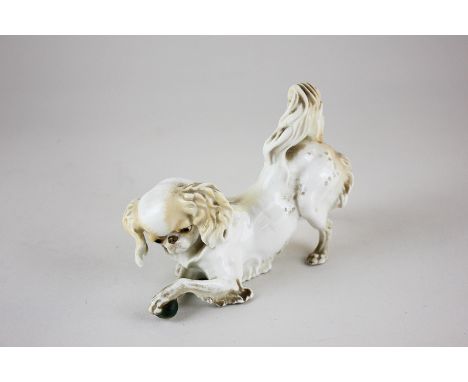 A Nymphenburg porcelain figure of a King Charles spaniel playing with a ball, marked Western Germany, 9.5cm high