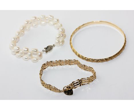 A light gauge 9ct gold gate link bracelet with padlock clasp; a 9ct gold bangle, 27g; a freshwater pearl bracelet