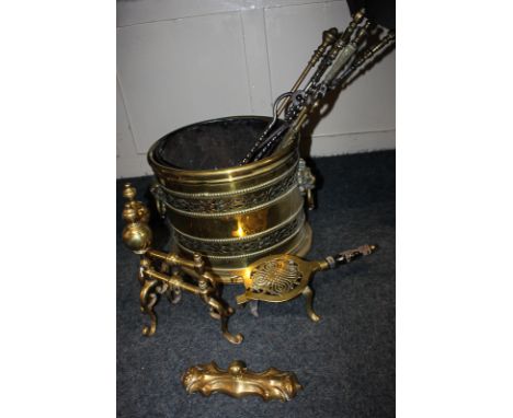 A brass oval coal scuttle with lion mask ring handles, two fire dogs, trivet and six tools