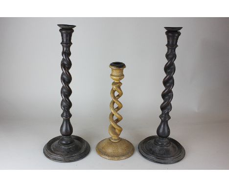 A pair of spiral turned wooden candlesticks on circular bases, 43cm, and a single light oak spiral turned candlestick, 32cm, 