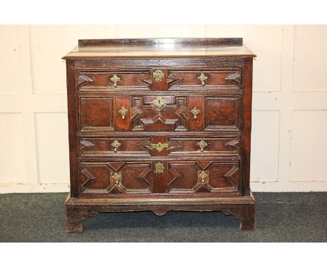 A Jacobean oak chest of four drawers with geometric panelled front and brass pear shaped drop handles, on bracket feet, 99cm