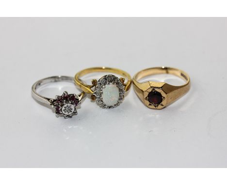 An opal and diamond cluster ring in 18ct gold; a ruby and diamond ring; a garnet ring