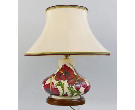 A Moorcroft table lamp, of flattened circular form, tube lined in the 'Hibiscus' pattern, on an ivory coloured ground with or