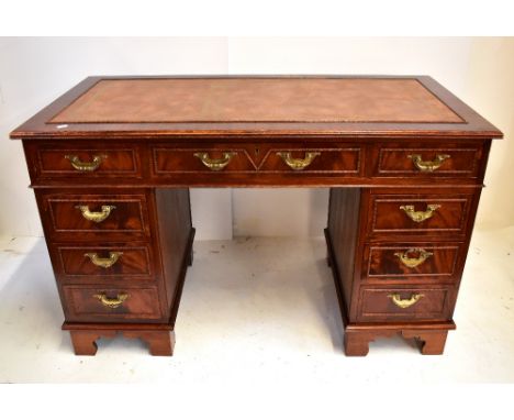 A reproduction mahogany twin pedestal desk, the top with inset gilt tooled tan leather writing surface above arrangement of t