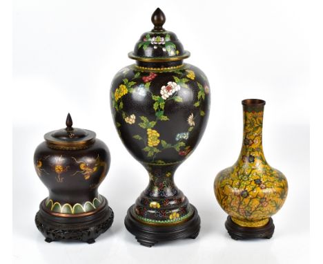 An early 20th century Chinese cloisonné enamel vase decorated with two five-clawed dragons and raised on a hardwood stand, he