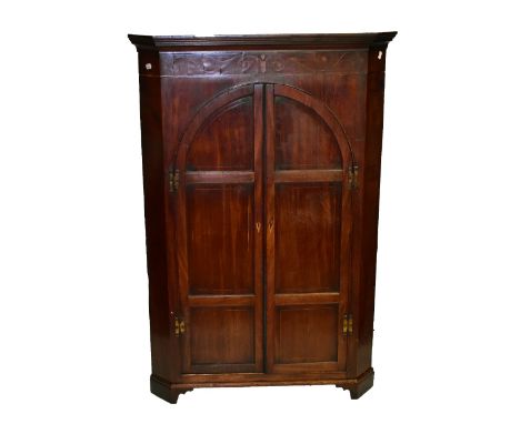 A George III mahogany corner cupboard with marquetry detail to frieze above twin arcaded and panelled doors enclosing three s