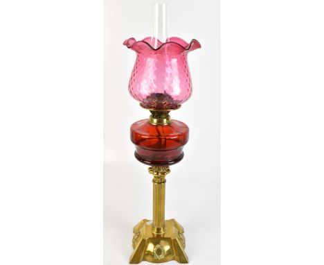A Victorian oil lamp with associated crimped cranberry glass shade, clear glass chimney, ruby glass reservoir and brass colum