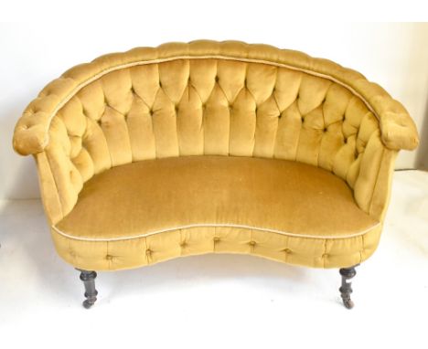 A Victorian button upholstered curved back settee with shaped frame and ring turned walnut front legs to castors, width 145cm