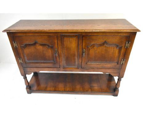 A reproduction oak sideboard of small proportions with two panelled doors raised on block feet, height 76cm, length 107.5cm, 