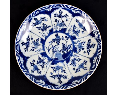 A Chinese Kangxi period porcelain charger painted in underglaze blue with floral decoration and with cafe-au-lait rim, with l