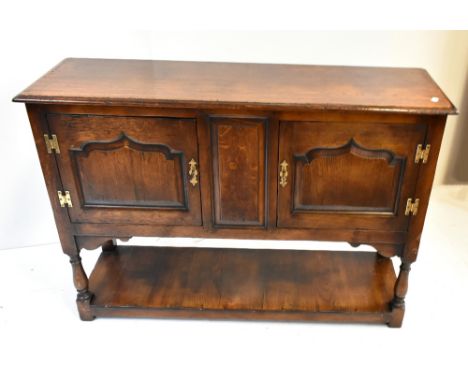 A reproduction oak dresser base with moulded rectangular top above twin fielded panelled doors on baluster ring turned block 