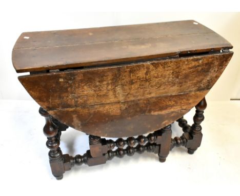 An 18th century oak gate leg drop leaf table raised on unusual turned and block supports united by stretchers, width 103cm (a