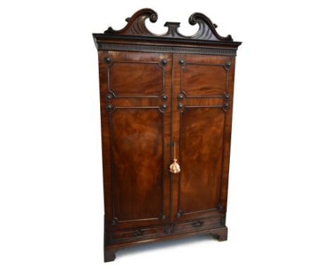 A good early 19th century mahogany wardrobe, the cornice with broken swan neck pediment above panelled doors and base of two 