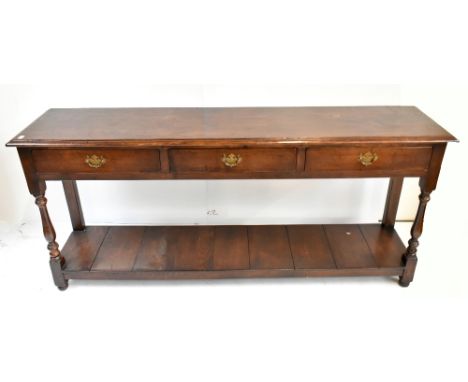 A reproduction oak dresser base with three frieze drawers raised on baluster ring turned and block supports united by an unde