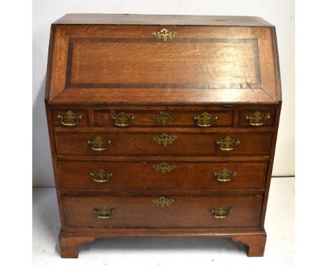A Georgian crossbanded and inlaid oak bureau, the fall front enclosing fitted compartment above three short and three long dr