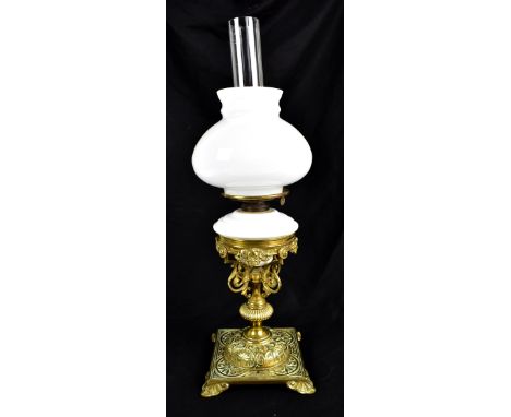 An early 20th century brass oil lamp with embossed Arts &amp; Crafts style decoration, with milk glass shade and reservoir, h