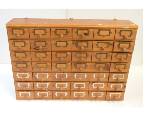 A vintage pine multi bank of forty-two short drawers each with brass clips for labelling and turned wooden handles, width 91c