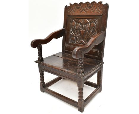 An 18th century oak Wainscot chair with carved foliate detail to seat back and bobbin turned detail on stretchered supports.A