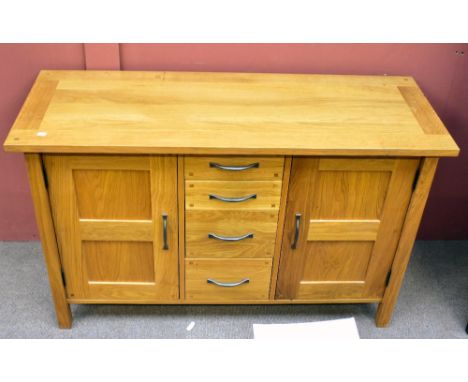 A modern oak sideboard with twin cupboard doors flanking a central column of four drawers, 130 x 48 x 80cm.Additional Informa