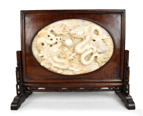 A large and impressive Chinese carved jade table screen, the central oval white jade panel depicting two four clawed dragons 