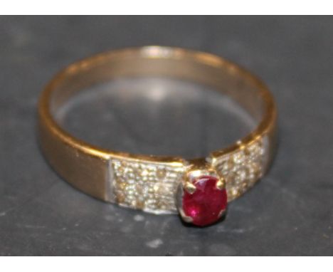 A YELLOW METAL RUBY AND DIAMOND RING WITH CENTRAL RAISED  CLAW SET RUBY FLANKED BY NINE BRILLIANT CUT DIAMONDS EITHER SIDE