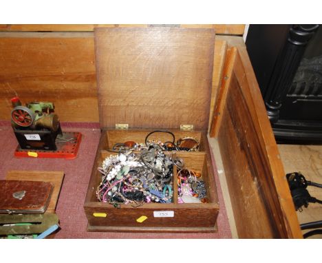 A wooden box with contents of various costume jewellery and a yellow metal bangle 