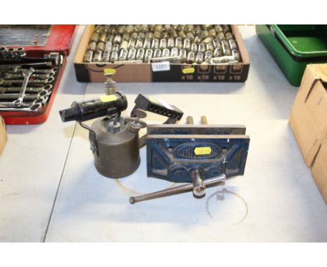 A vintage brass blow lamp together with a small bench vice