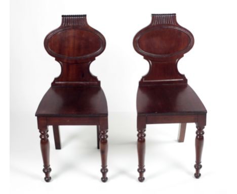 A pair of early 19th Century carved mahogany Hall Chairs, with oval panel backs and front turned legs. (2)