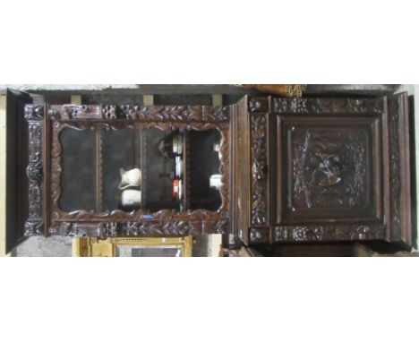 A profusely carved tall Victorian period dark oak Bookcase, the top with single glazed door flanked with mask, leaves and two