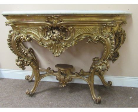 An very fine early 19th Century carved giltwood Console or Side Table, the serpentine shaped moulded marble top, over a profu