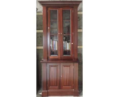 A matching pair of tall mahogany Bookcases, of narrow proportions, each with moulded cornice over two glazed doors and two pa