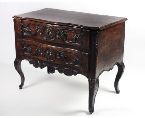 An 18th Century French Provincial walnut Commode, the shaped top over two carved frieze drawers with heavy brass handles, on 
