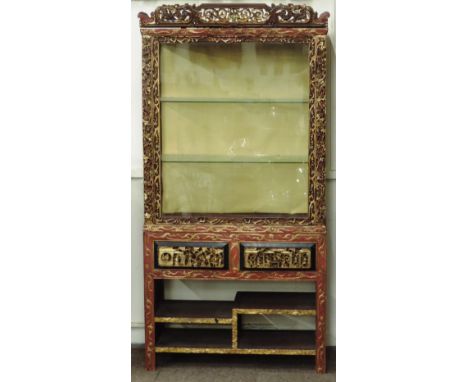 A late 19th Century / early 20th Century Chinese red lacquered Display Cabinet, the pierced and carved pediment over a large 