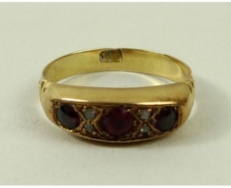 An 18ct gold three stone ring, set with three garnets divided by four small diamonds, size O, 3.4g. 