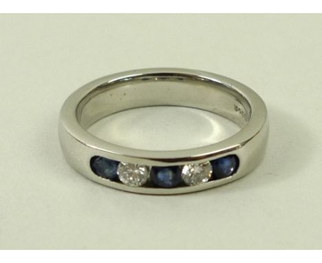 A platinum, diamond and sapphire ring, with three sapphires set into the ring, divided by two diamonds, size L, 7g. 