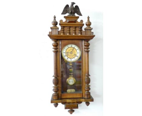 An early 20th century mahogany wall clock with enamel chapter dial, Roman numerals and having a carved eagle to the pediment,