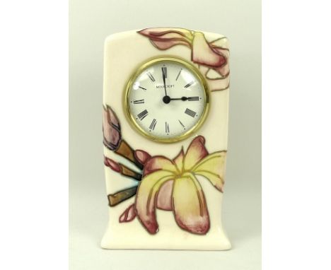A Moorcroft mantel clock, in magnolia pattern, the circular face with Arabic numerals, 9 by 5 by 16cm, boxed. 