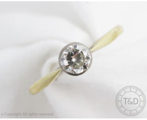 A solitaire diamond ring, the old brilliant cut diamond within white metal collet setting, slender shoulders and plain yellow