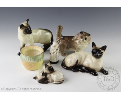 Four Beswick cats comprising; a Persian cat modelled standing in grey gloss, a Siamese cat modelled standing, Siamese laying 