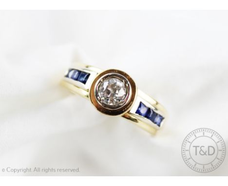 A diamond and sapphire set ring, designed as a central diamond, collet set, within square cut sapphire set shoulders, all set