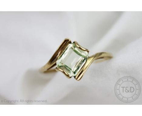 A citrine set ring, of cross-over design and set with a central emerald cut stone, all set in yellow metal, unmarked, size U,