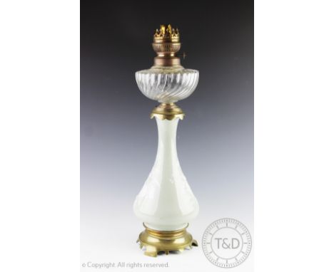 A French porcelain Pate-sur-pate oil lamp, the waisted porcelain body decorated in relief with wild floral sprays, supporting
