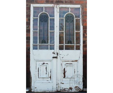 A pair of Edwardian Scottish doors, each inset with an arched stained glass panel of a stylized flower after Charles Rennie M