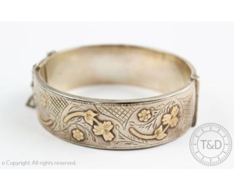 A silver and gold hinged bangle, Deakin and Francis Birmingham early 20th century, of hinged form and with floral and foliate