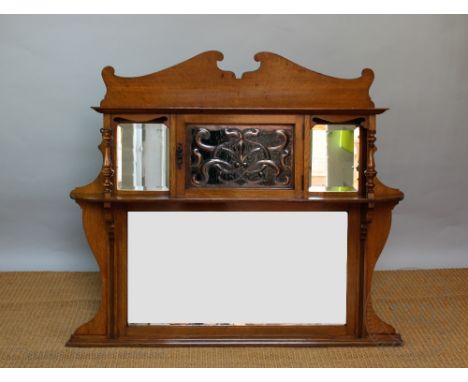 A late Victorian Art and Crafts golden oak overmantle mirror, in the manner of Liberty &amp; Co, with shaped mirror above a f