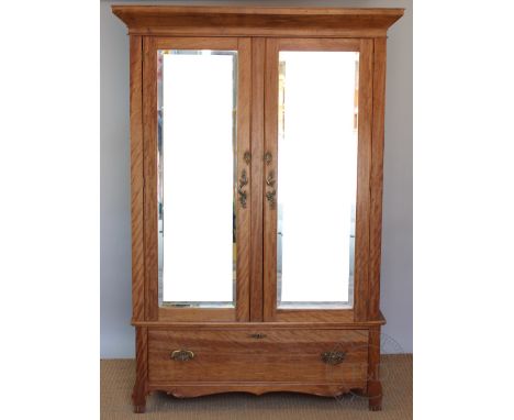An Edwardian satin birch wardrobe, with two mirrored doors above a drawer, on bracket feet, 193cm H x 130cm W x 56cm D