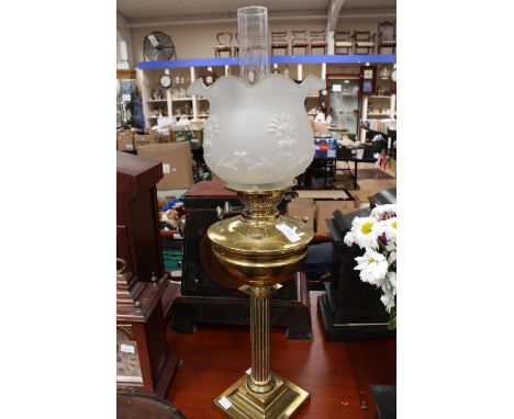 A twin burner brass paraffin lamp, with original globe opaque glass shade, and glass chimney