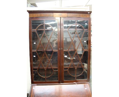 A George III mahogany bureau bookcase, the glazed bookcase top added later, the bureau opening to reveal fitted interior with