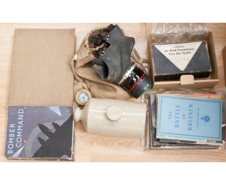 A World War II gas mask in holder, air raid first aid kit, stone flagon, World War II related books and a brass compass  